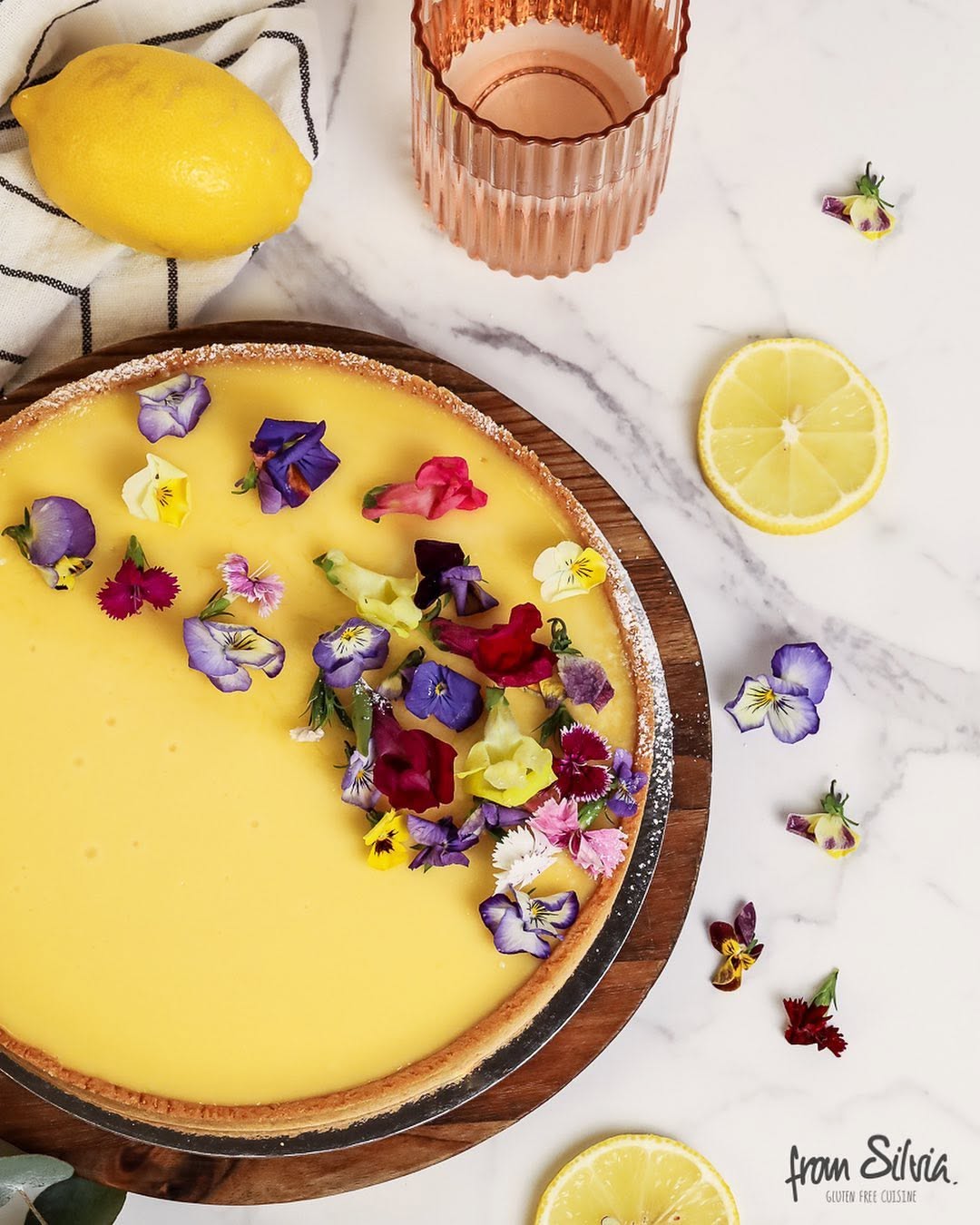 Lemon tart with edible flowers on a marble table
